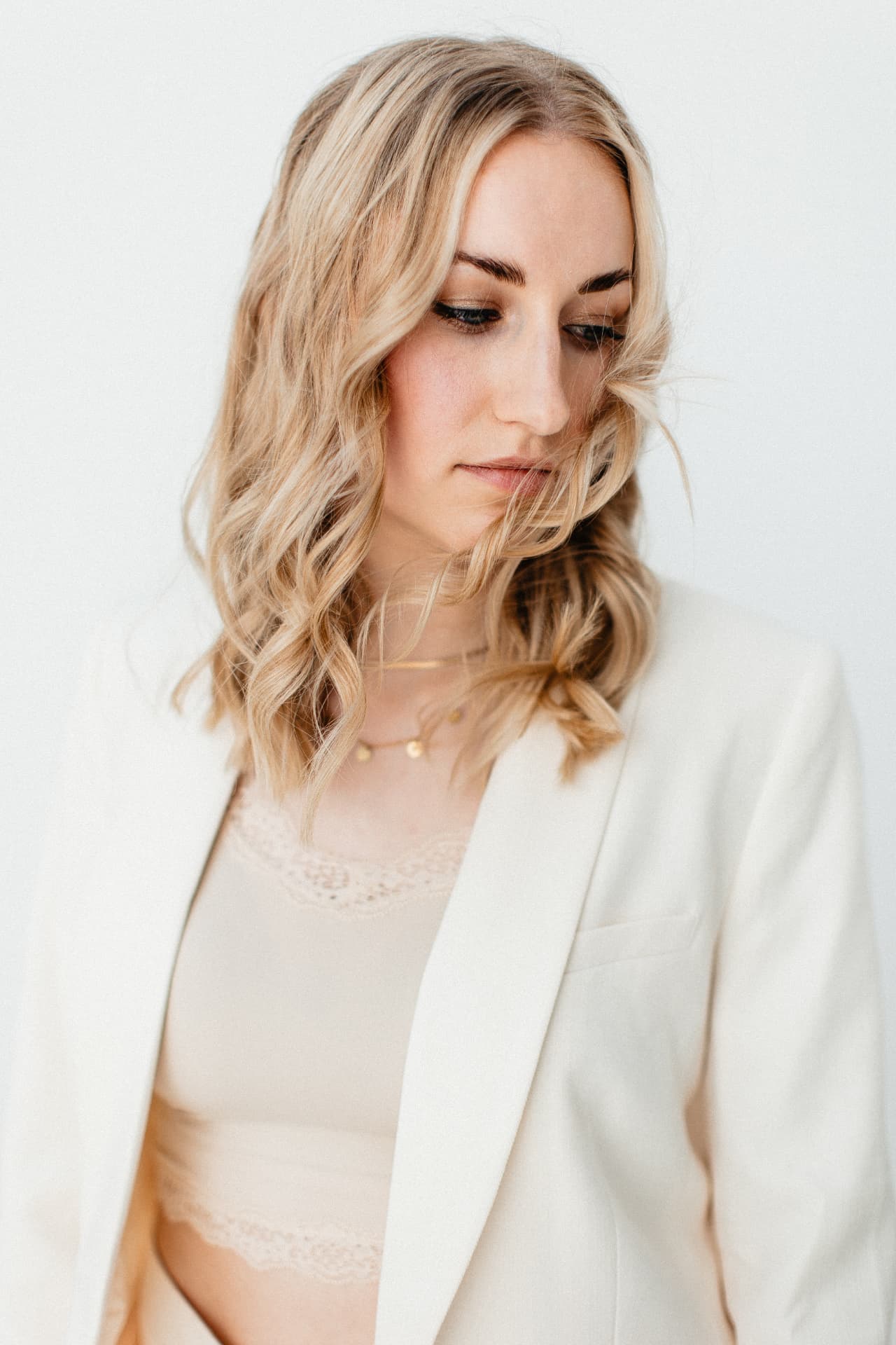 Heike mit gesenktem Blick im hellen Blazer